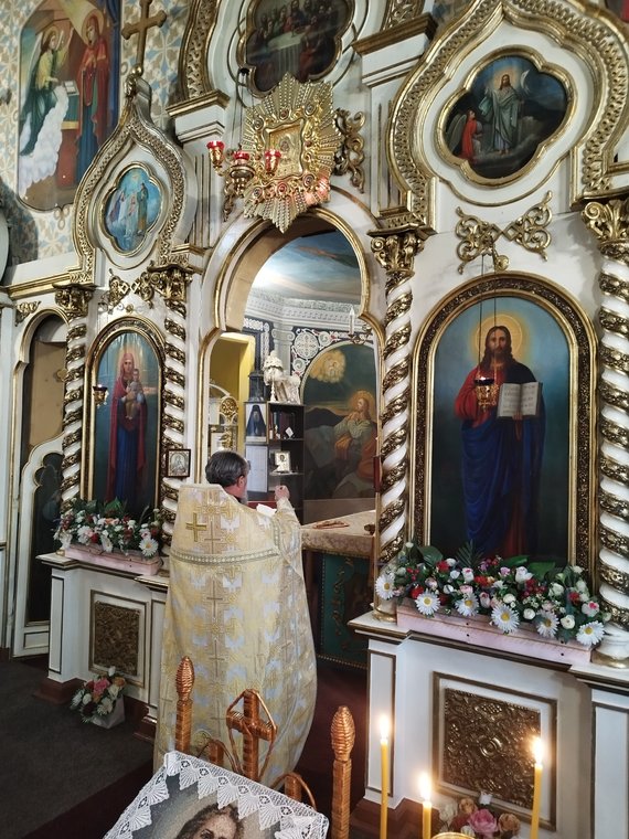 Părintele, în veșminte aurii, la iconostas