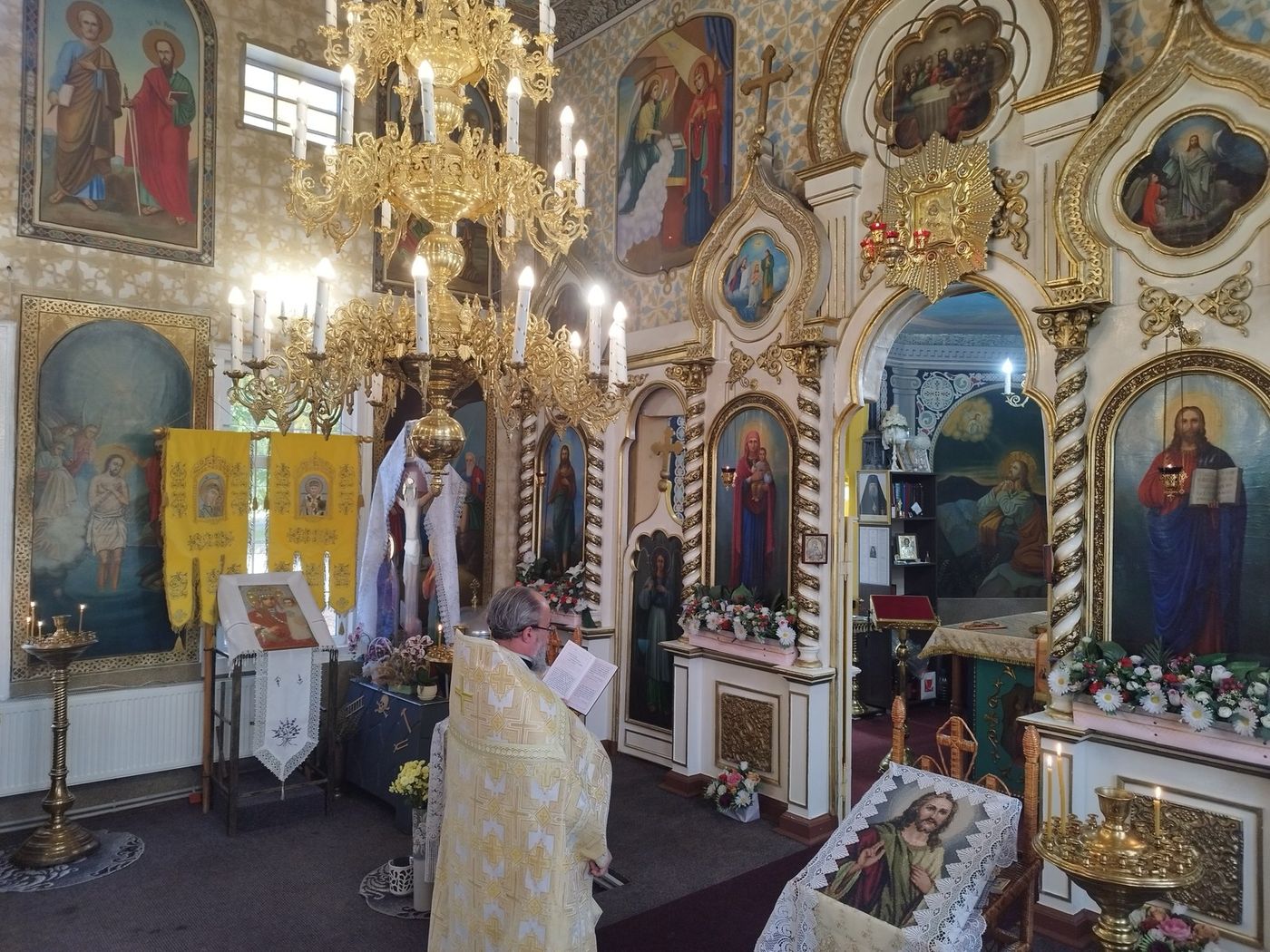 Părintele citind, în fața iconostasului