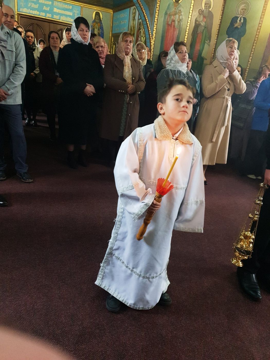 Băiețelul în stihar, cu lumânarea, în mijlocul bisericii