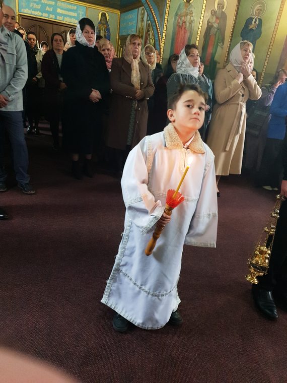 Băiețelul în stihar, cu lumânarea, în mijlocul bisericii